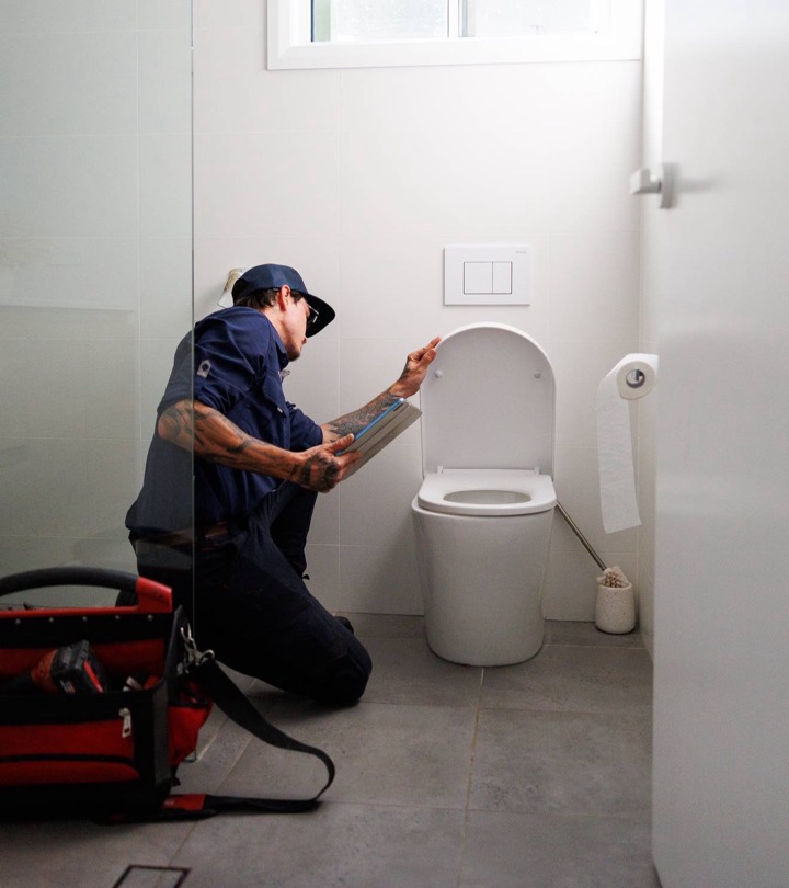 S&J plumber kneeling beside a toilet with his tool bag, clearing a blocked toilet
