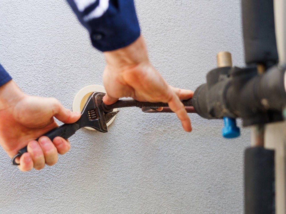 Hands tightening a pipe fitting with a wrench